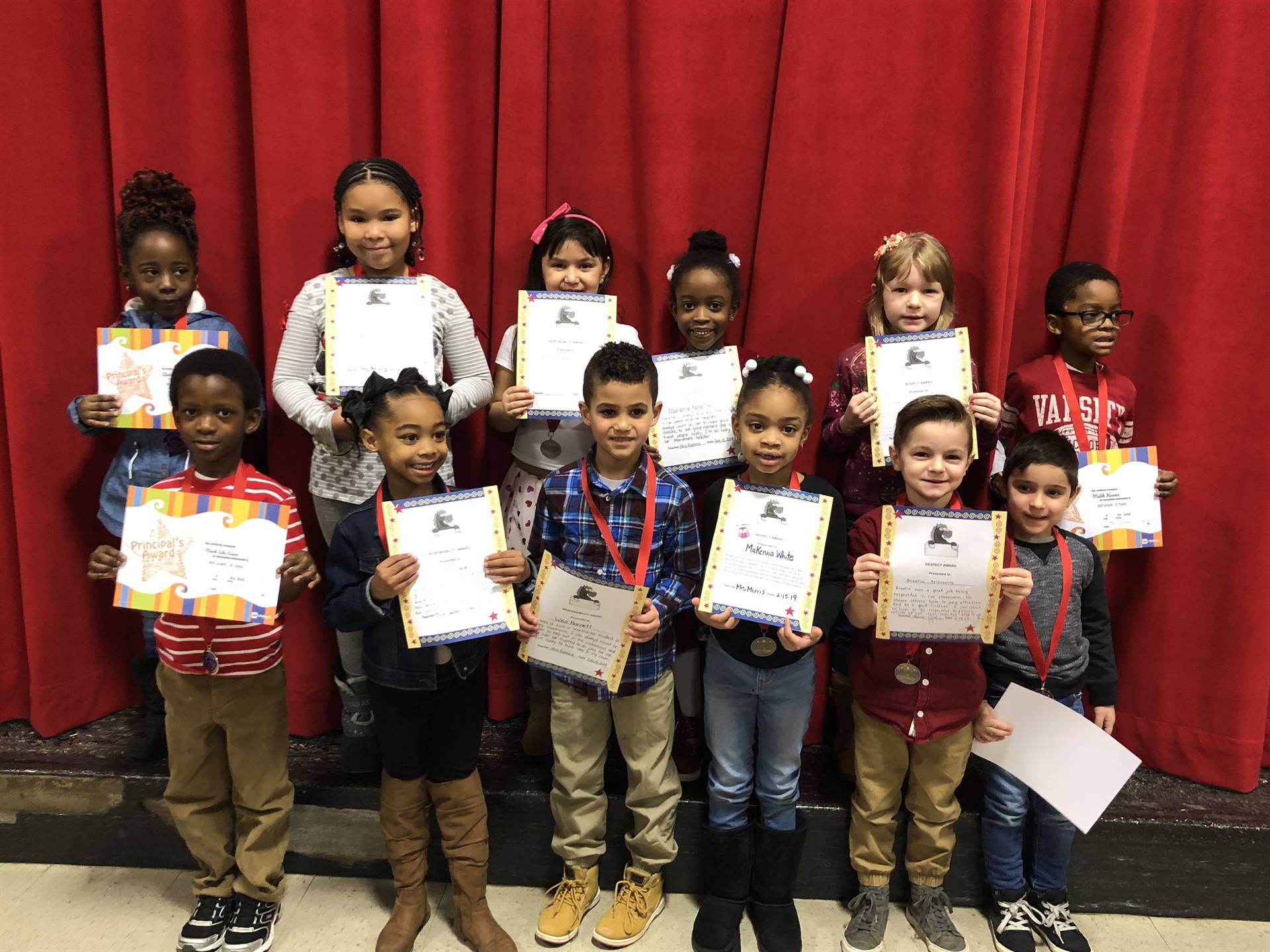 students holding paper certificates